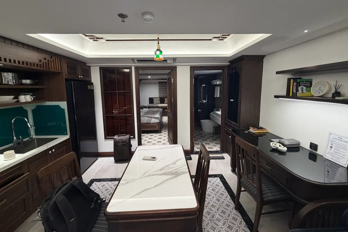 Jake’s apartment: a kitchenette on the left, a marble-topped dining table in the middle, a desk and shelves on the right, and the bedroom through the far door