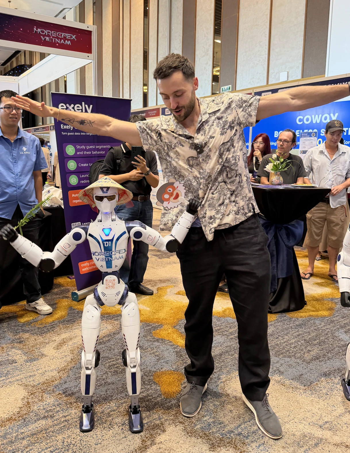 Jake beside a humanoid robot at an exhibition in Vietnam